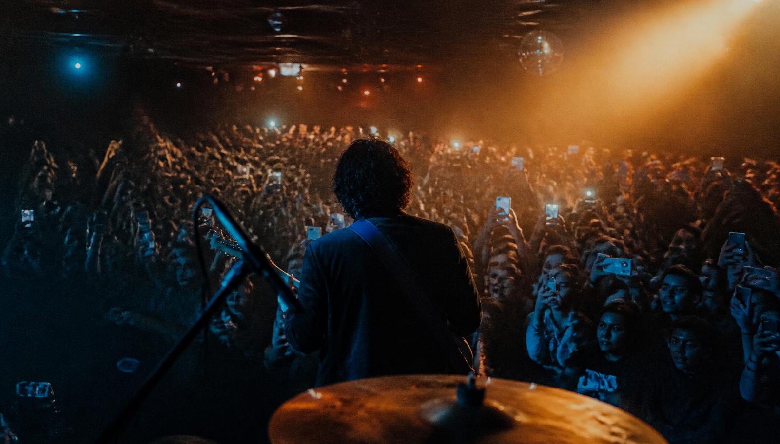 A crowd at a small live venue with phones raised